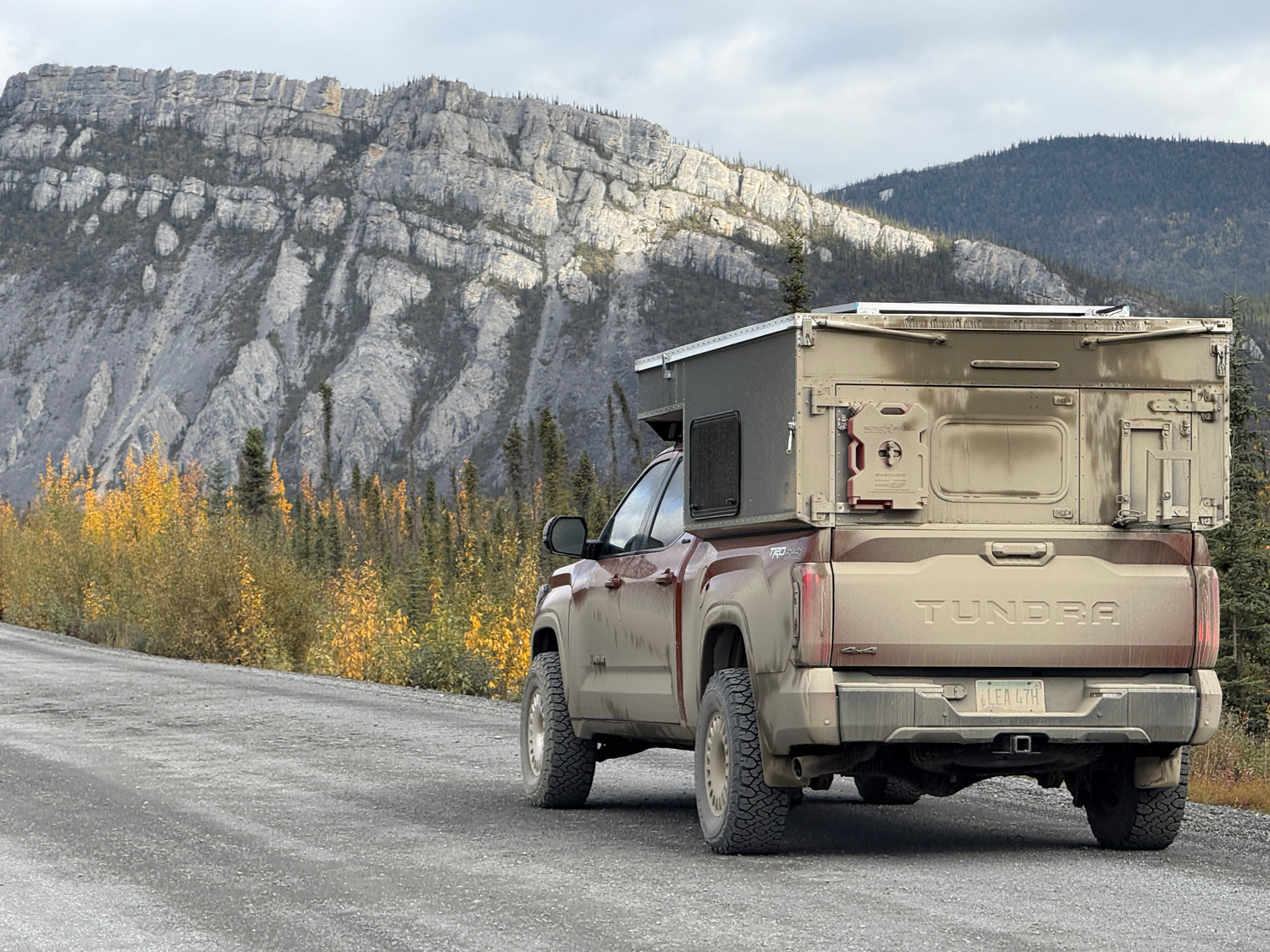 Toyota Tundra truck with a camper shell on a mountain road