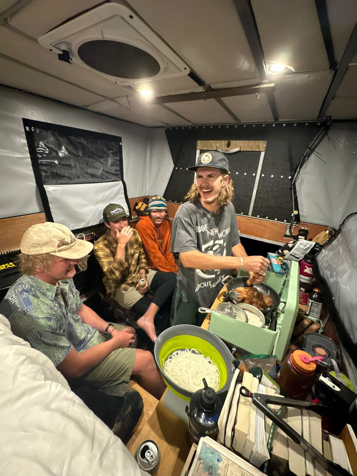 6 people cooking dinner inside their overland camper shell on a Toyota Tundra. 