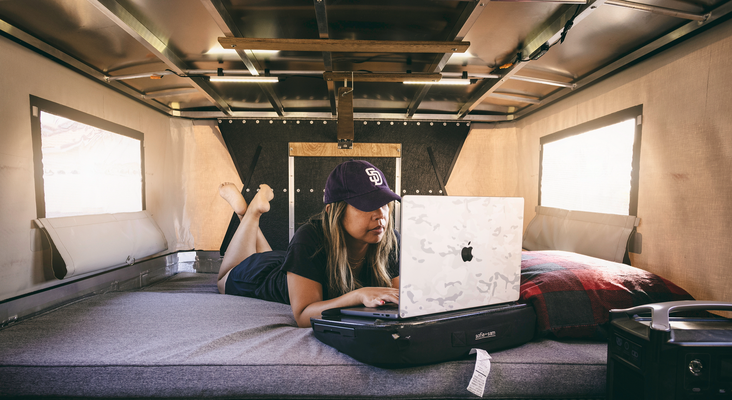 Person working on Laptop on OVRLND Pop Up Camper Bed