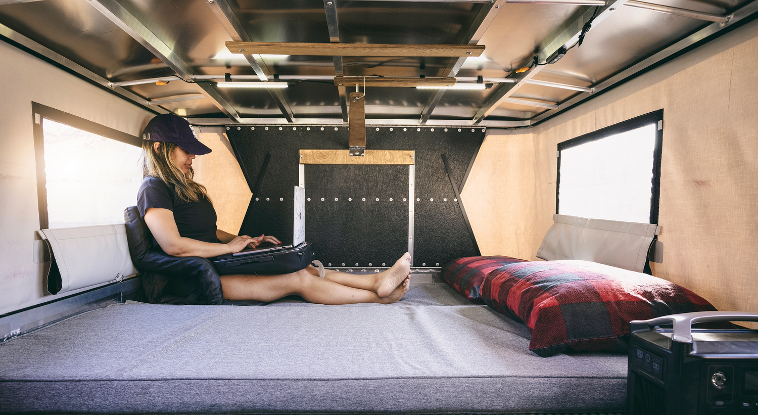 Person working on Laptop on OVRLND Pop Up Camper Bed