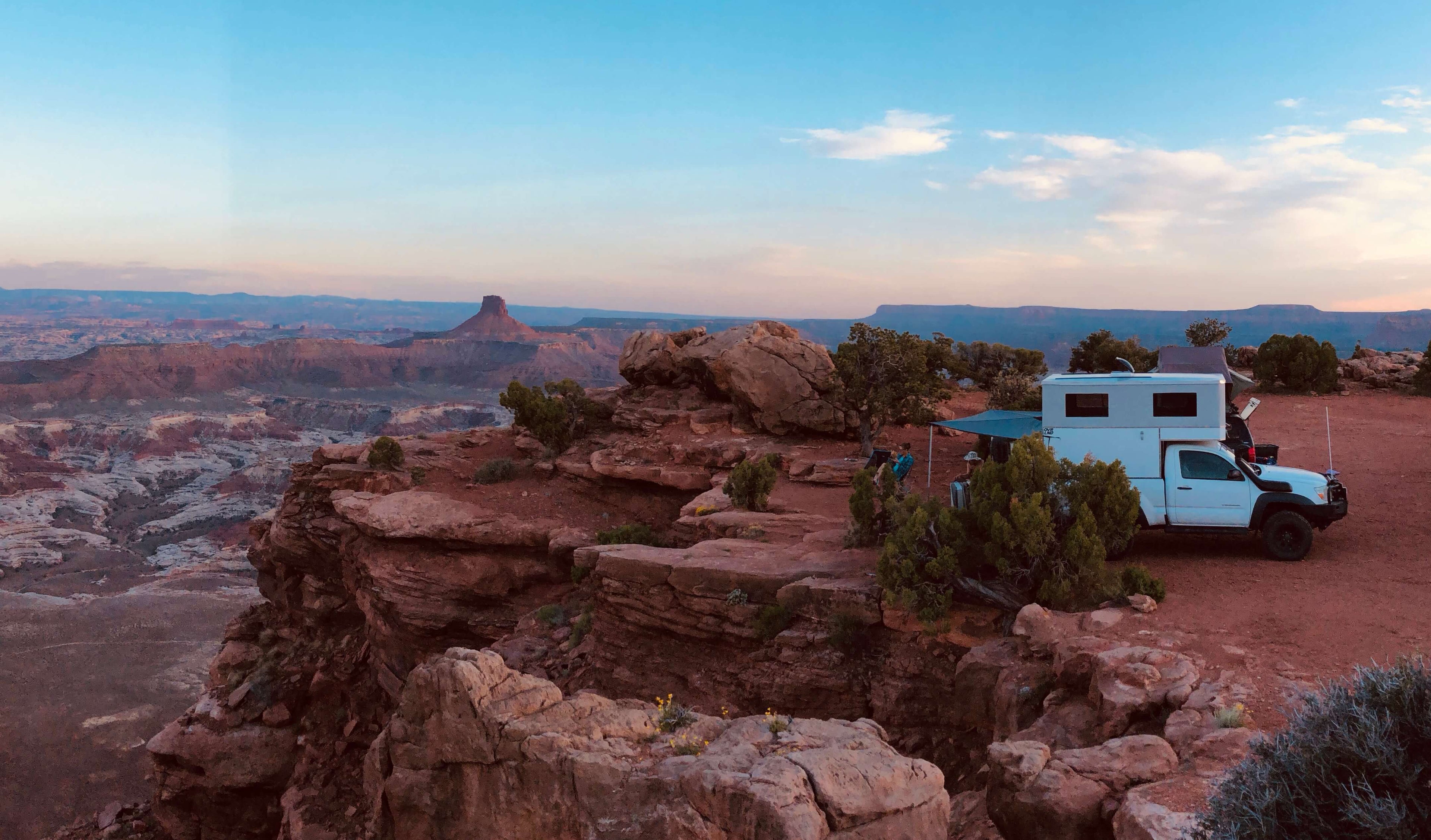 Cover photo with Pop-up camper on cliff edge. The truck is a white Toyota Tacoma with white camper.